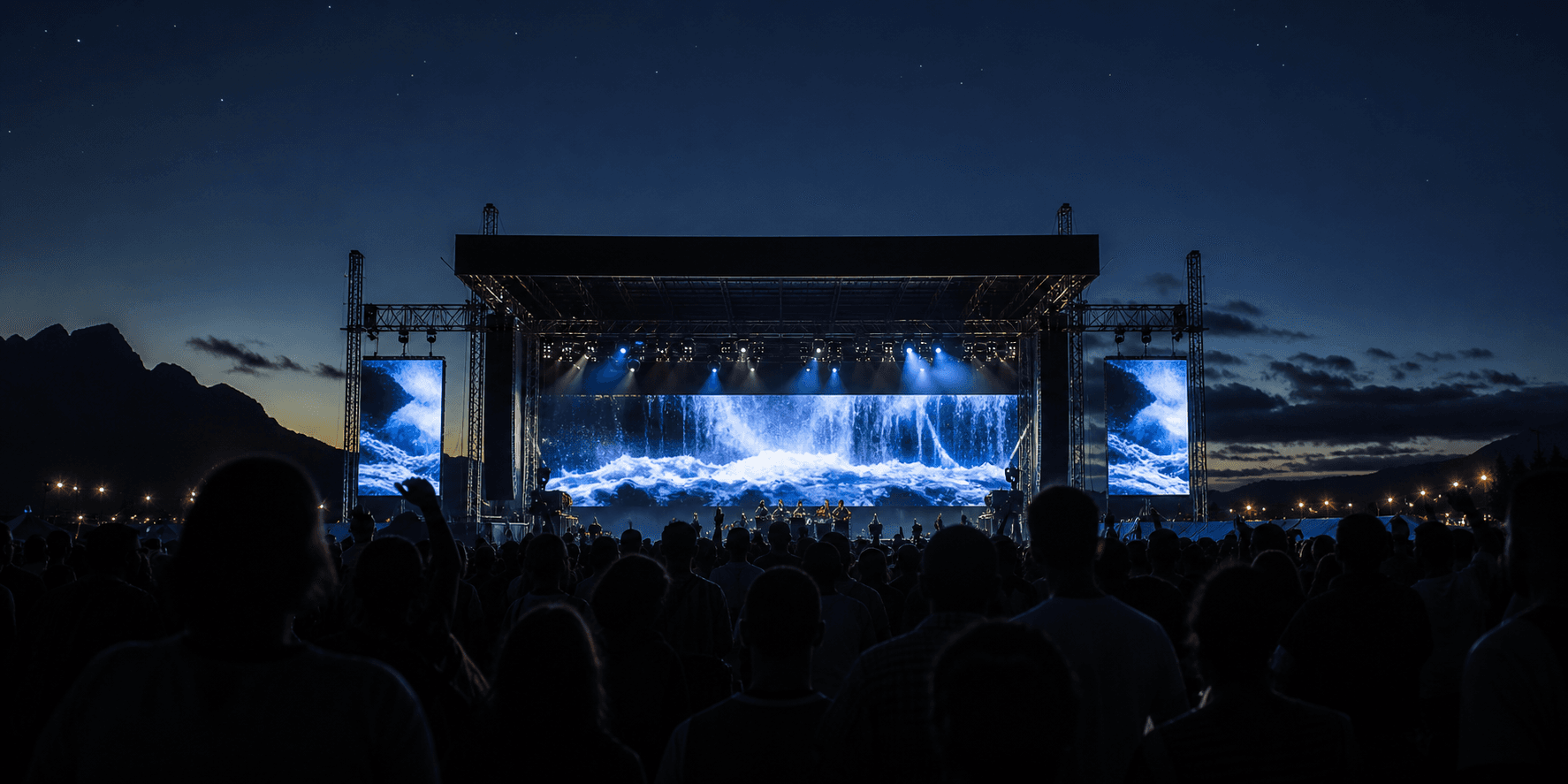 Large outdoor concert stage at blue hour with modular LED walls and an audience